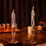 Zwei elegante Kerzen in Glasvasen auf einem dunklen Holztisch, ideal für wissenschaftliche Dekorationen und stilvolle Raumgestaltung.