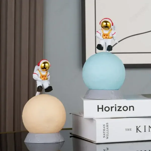 Zwei kleine Astronautenfiguren in Raumanzügen mit goldenen Helmen, die auf bunten, leuchtenden Planeten sitzen, ideal für wissenschaftliche Dekorationen und Raumfahrt-Themen.