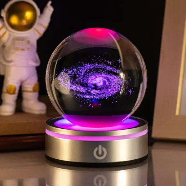 Dekorative Kristallkugel mit galaktischem Universum-Design, leuchtend in Pink und Blau, auf einem modernen Basis. Perfekt für Wissenschafts- und Raumfahrt-Dekorationen.