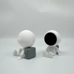 Niedliche Astronautenfigur mit einem schwarzen, leeren Raumhelm, sitzend auf einem weißen Hintergrund, ideal für wissenschaftliche Dekorationen und Raumfahrt-Themen.
