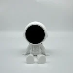 Niedliches Weltraum-Roboter Spielzeug mit schwarzem Gesicht, sitzend auf weißem Hintergrund, ideal für Science-Fiction- und Robotik-Enthusiasten.