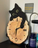 Schwarze Katzenuhr aus Holz mit gelben Augen, die auf einer Baumstamm-Optik sitzt, ideal als dekoratives Element für Katzenliebhaber und Naturfans.