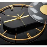 Elegante Wanduhr mit schwarzen Zifferblatt, goldenen Zeigern und Federn im Design, ideal für moderne Raumdekorationen.