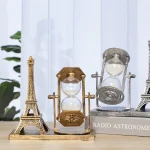 Kleine Eiffelturm-Modelle und Sanduhren als dekorative wissenschaftliche Objekte auf einem Tisch, ideal für Sammler und Dekoration im wissenschaftlichen Stil.