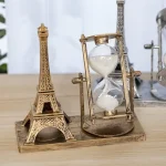 Miniatur Eiffelturm und antike Sanduhr auf Holzplatte, dekoratives Wissenschafts- und Requisit-Set für Sammler und Dekoration.
