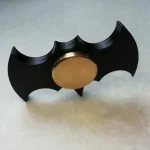Dekoratives Batman-Objekt mit schwarzem Flügel-Design und goldener Mitte.