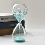 Elegante Glas-Sanduhr mit blauer Sanduhrfüllung und schwebenden Luftblasen, ideal für wissenschaftliche Dekorationen und moderne Raumgestaltung.