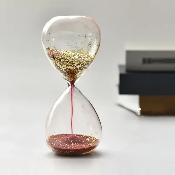 Dekorative Sanduhr mit goldenen Partikeln und rotem Sand, ideal als wissenschaftliches Dekorationsstück oder Geschenk.