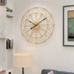 Moderne Wanduhr mit geometrischem, goldfarbenem Rahmen und schwarzen Zeigern, ideal für zeitgenössische Wohnräume und Büros.