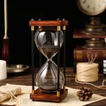 Elegante Sanduhr mit Holzrahmen und schwarzem Sand, ideal als wissenschaftliches Dekorationsstück oder Geschenk.