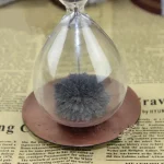 Künstliches Moos in einer transparenten Glaskugel, die auf einem Holzsockel steht, ideal für wissenschaftliche Dekorationen oder als einzigartiges Natur-Accessoire.
