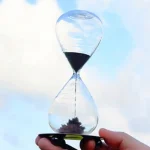 Sanduhr aus Glas mit schwarzem Sand, zeigt den Fluss der Zeit in einem modernen Design.