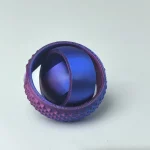 Wissenschaftliches Modell in Blau und Lila, bestehend aus zwei ineinander verschlungenen Ringen mit strukturierter Oberfläche, auf hellem Hintergrund.