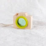 Holzspielzeugkamera mit grünem Objektiv, ideal für Kinder und Dekoration im Wissenschaftsstil.