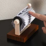 Wissenschaftliches Experiment mit Papierwelle, bei dem eine Hand eine Papierbahn auf einem mechanischen Gerät bewegt, um physikalische Prinzipien zu demonstrieren.