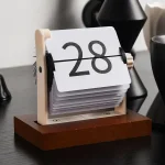 Vintage-Flip-Calendar mit weißen Zahlen auf schwarzem Hintergrund, auf Holzbasis, dekoratives Element für Büro oder Zuhause.