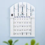 Wandkalender mit Segelboot-Motiv, zeigt Monats- und Tagesübersicht, ideal für maritime Dekorationen.