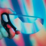 Hand hält ein Glasobjekt mit bunten Lichtreflexen, das wissenschaftliche Dekoration oder Kunstobjekt darstellt.