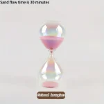 Bunte Sanduhr mit pinkem Sand, zeigt eine Laufzeit von 30 Minuten, ideal für Zeitmessung bei Spielen oder Kochen.