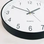 Moderne Wanduhr mit Quarzmechanismus und klarer Zifferblattgestaltung.