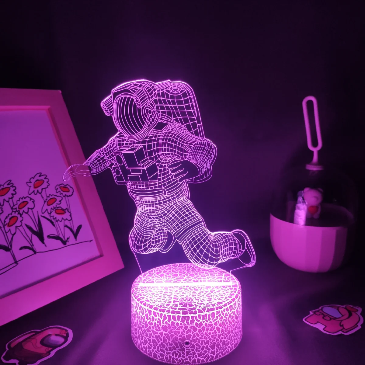 3D-gedruckter Astronaut mit LED-Beleuchtung, leuchtet in Pink, auf einem dunklen Hintergrund.