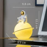Dekorative Planetlampe mit Astronautenfigur, ideal für Science-Fiction- und Weltraumthemen, leuchtet gelb und misst ca. 12,1 cm in Höhe.