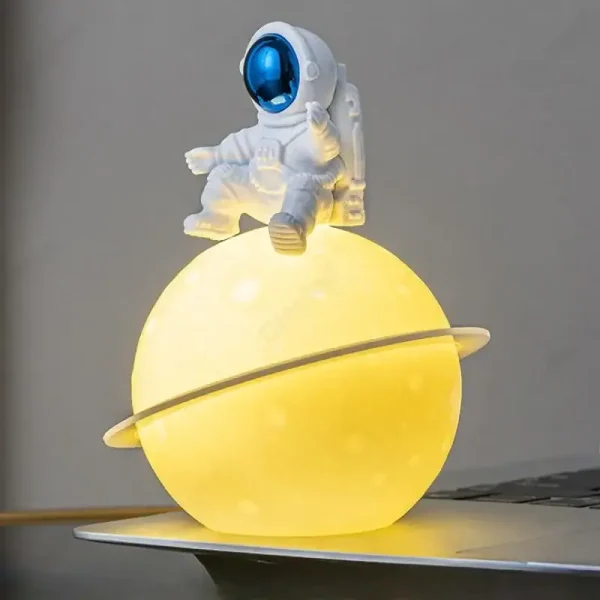 Kleines Astronautenmodell auf einer leuchtenden Planetlampe, ideal für Science-Fiction-Dekorationen und wissenschaftliche Themen.