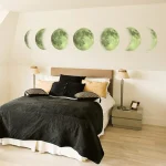 Wanddekoration mit verschiedenen Mondphasen, die über dem Bett in einem modernen Schlafzimmer angebracht sind.