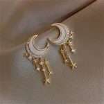 Elegante goldene Ohrringe mit Mond- und Sternmotiven, verziert mit kleinen Kristallen und Hängern, ideal für stilvolle Anlässe.