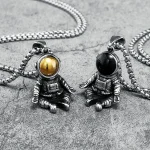 Zwei Astronauten-Anhänger aus Metall mit unterschiedlichen Helmfarben, auf einer grauen Oberfläche. Perfekt für Science-Gadget- und Weltraum-Liebhaber.