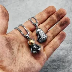 Detailaufnahme einer Kette mit Raumschiff-Anhänger, der auf einer Hand liegt, die schmutzig und staubig ist.