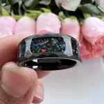 Schwarzer Ring mit buntem Sternenstaub-Design.
