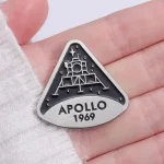 Detailaufnahme eines Apollo 1969 Medaillons mit Raumfahrtsymbolen, das auf einer Hand liegt, symbolisiert die Mondlandung von 1969.