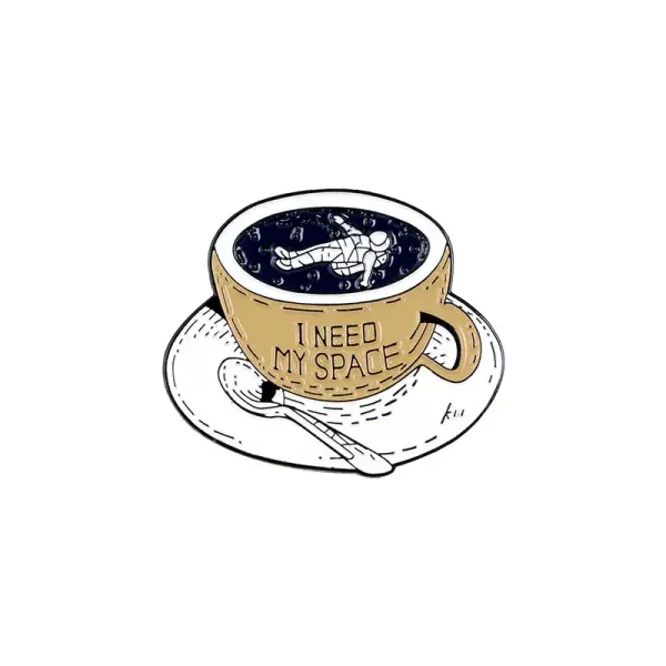 Kaffeetasse mit Astronauten-Design und der Aufschrift "I NEED MY SPACE" auf weißem Hintergrund, gefüllt mit schwarzem Kaffee, auf einem weißen Unterteller mit Löffel.