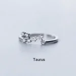 Eleganter Ring mit Taurus-Sternzeichen, verziert mit kleinen funkelnden Steinen, auf hellem Hintergrund.