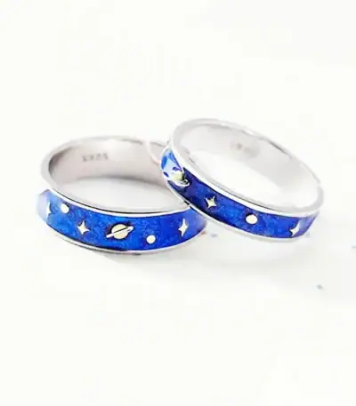 Zwei Edelstahlringe mit Weltraummotiv, Sternen und Planeten, auf weißem Hintergrund.