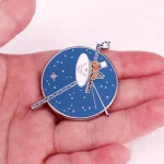 Detailliertes Medaillon mit Satellit und Raumstation, das die Raumfahrt symbolisiert, auf einer Hand liegend. Perfekt für Wissenschafts- und Technikliebhaber.