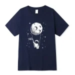 Dunkelblaues T-Shirt mit weißem Astronauten, der an einem Faden an einem Mond schaukelt, geeignet für Science-Fans und Astronomie-Enthusiasten.