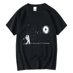 Schwarzes T-Shirt mit Astronaut und Galaxie-Design, das einen Astronauten zeigt, der in den Weltraum blickt, mit einem schwarzen Loch und Sternen im Hintergrund.