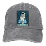 Grauer Baseball-Cap mit aufgenähtem Astronauten-Design, der einen Astronauten im Raumanzug zeigt, der zwei blauen Taschen trägt.