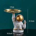 Dekorativer Teelichthalter in Form eines Astronauten mit goldener Helmkappe, der eine goldene Schale hält, ideal für Raumdekorationen und Science-Fiction-Themen.