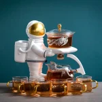 Deko-Objekt eines Astronauten in Raumanzug, der eine Teekanne mit Drachenmotiv hält, umgeben von acht Teetassen, ideal für Science-Fiction- und Weltraumthemen.
