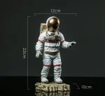 Detailaufnahme einer Raumfahrerfigur mit goldener Helm, Maße: 12cm breit, 22cm hoch, 10cm Basis, auf dunklem Hintergrund.