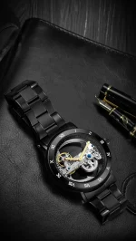 Hochwertige schwarze Armbanduhr mit offenem Uhrwerk, das das mechanische Innenleben zeigt, auf einem schwarzen Lederetui mit Füllfederhalter.