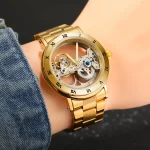 Armbanduhr mit offenem, mechanischem Uhrwerk und goldfarbenem Gehäuse, getragen am Handgelenk.