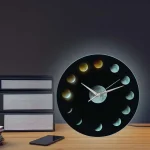 Moderne Wanduhr mit Mondphasen-Design, zeigt die verschiedenen Phasen des Mondes in einem stilvollen schwarzen Zifferblatt. Perfekt für Wissenschafts- und Dekorationsliebhaber.
