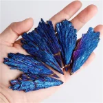 Nahaufnahme von blauen, kristallinen Edelstein-Formationen, die in einer Hand gehalten werden, mit schillernden Oberflächen und scharfen Kanten.