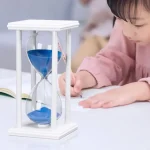 Kinder experimentieren mit einer Sanduhr, die blaue Flüssigkeit enthält, auf einem weißen Tisch. Perfekt für Bildungs- und Wissenschaftsdekorationen.