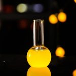 Reagenzglas mit gelber Flüssigkeit vor dunklem Hintergrund.