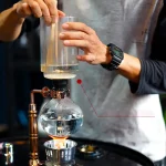 Wissenschaftler führt chemisches Experiment mit Glasapparatur durch, Wasser und Reagenzien in einem Labor.